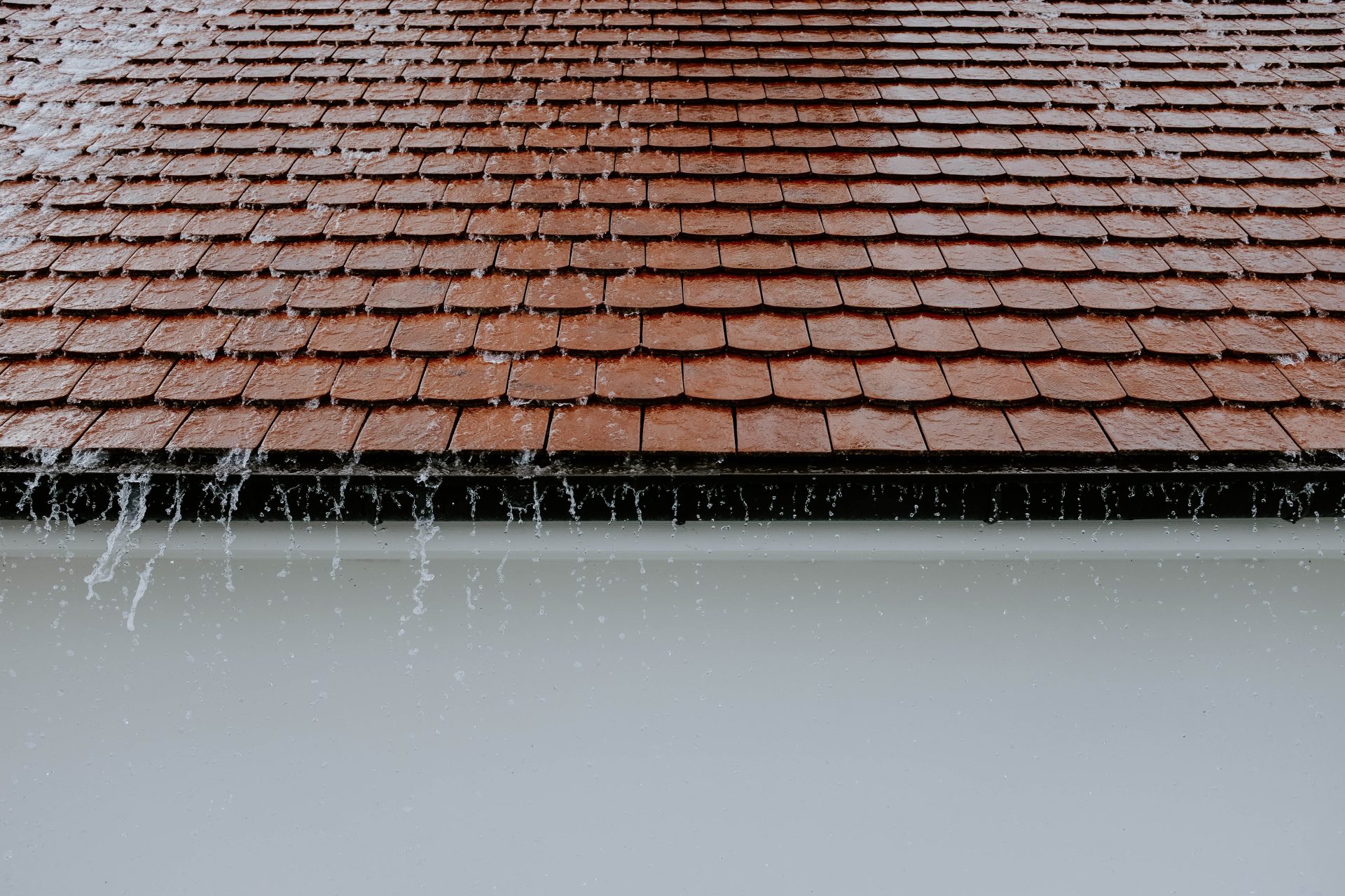 rain rushing off of a red tiled roof