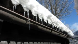 snow and icicles handing off edge of home's roof
