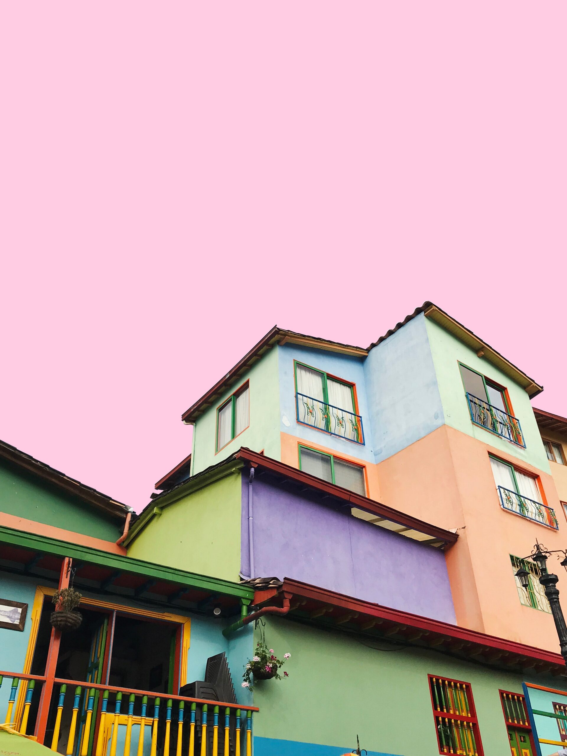 apartment building painted in bright pastel colors against a light pink sky